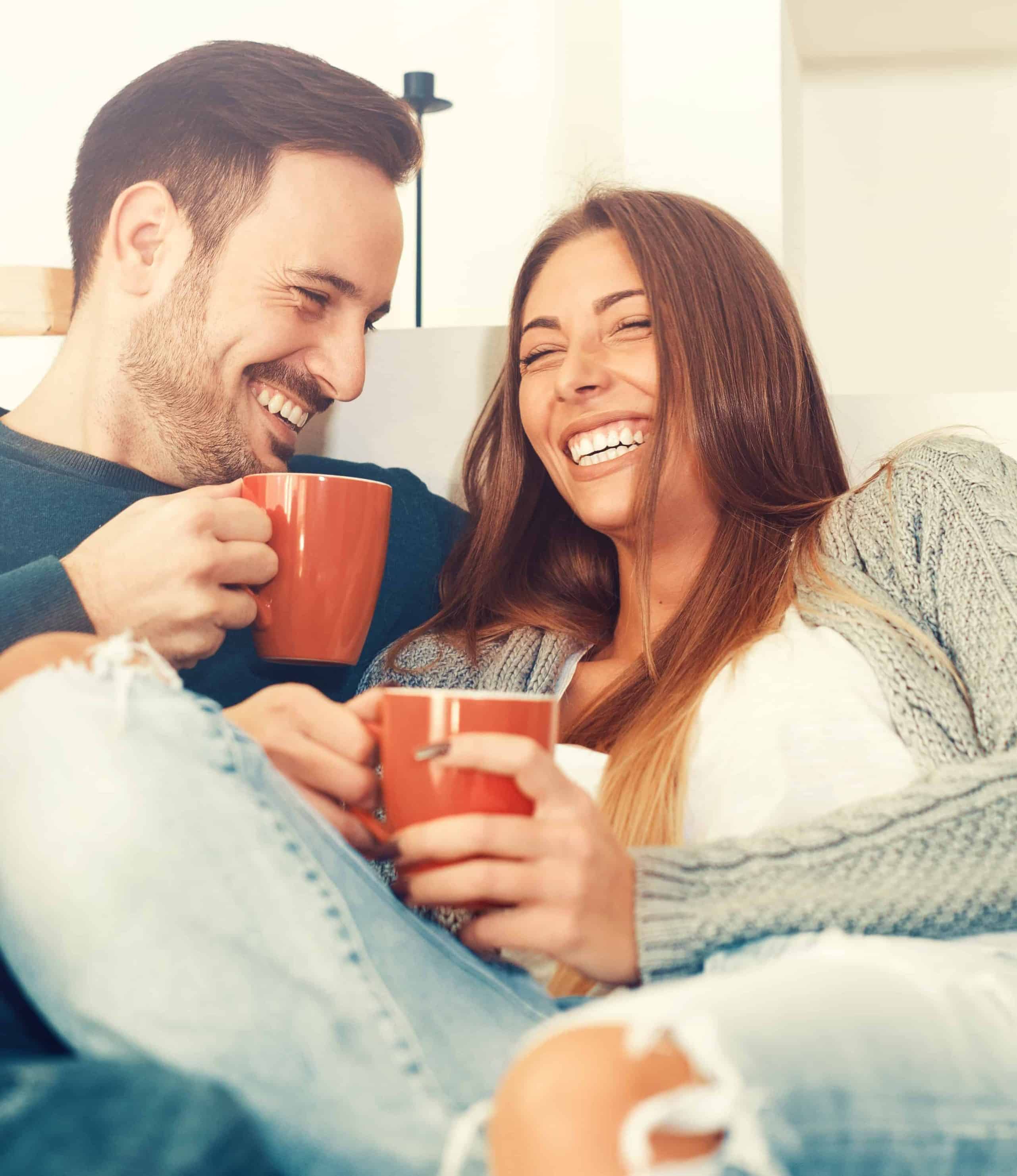 Couple souriant avec des tasses de café dans un intérieur lumineux et propre, grâce à Nettoyage Impérial.