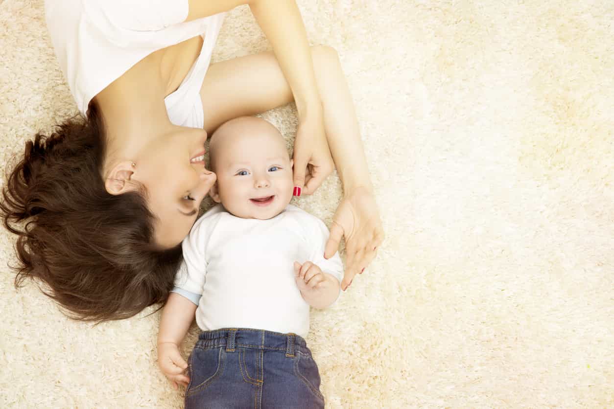 Mère et bébé heureux allongés sur un tapis propre, fraîcheur garantie par Nettoyage Impérial